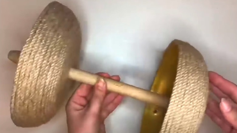 Woman showing off finished two-tier braided bathroom storage made from two frying pans