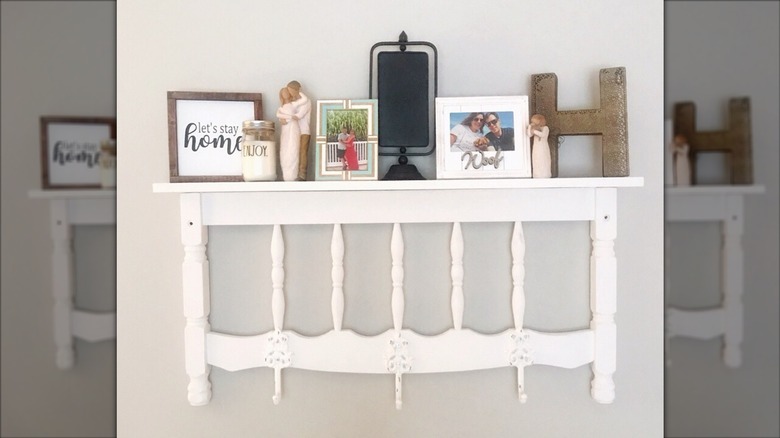 Repurposed white spindle headboard being used as a wall storage shelf for decor items