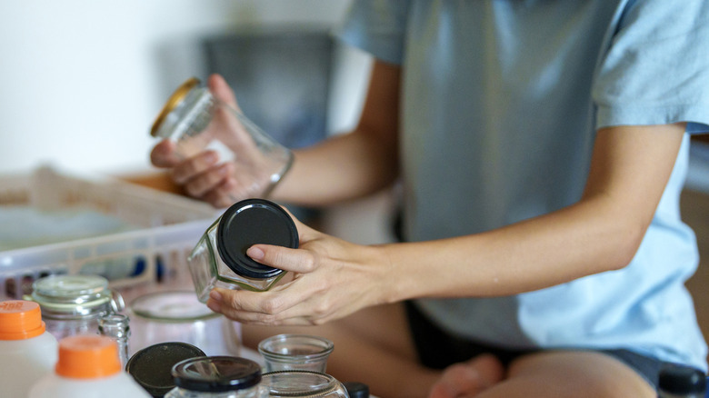 An anonymous woman's hands reaching for a empty jars