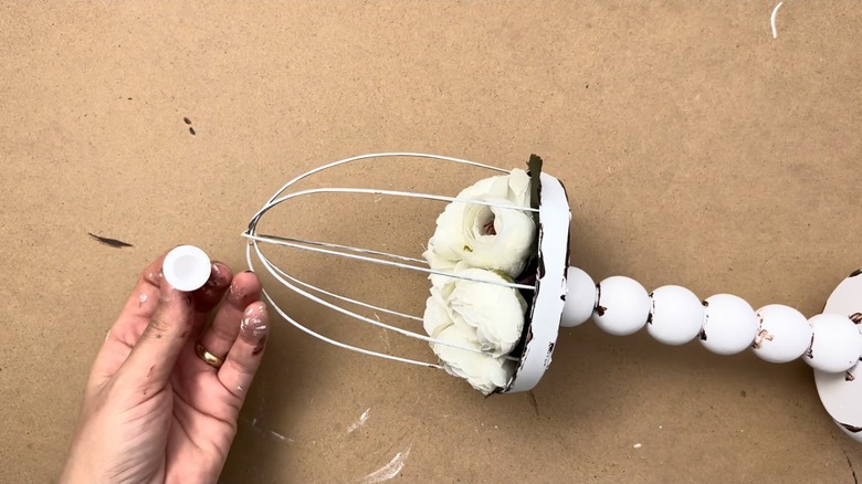 Person making decorative bird cage stand using whisk tines
