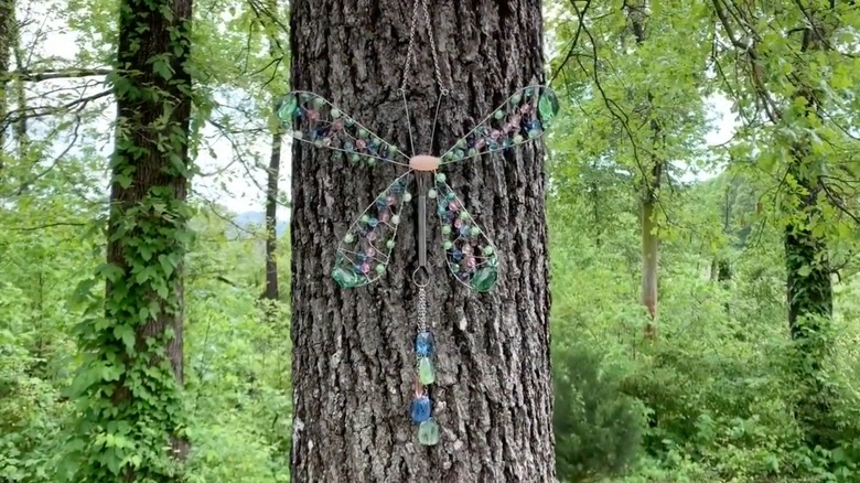 Dragonfly-shaped suncatcher hanging on tree