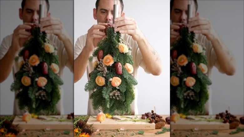 Man creating hanging bouquet using large whisk