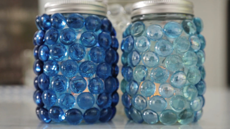 Two lanterns made with Mason jars covered in marbles