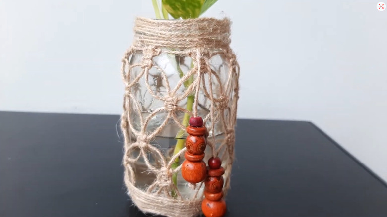Jar covered in twine to create a macrame look with a plant inside