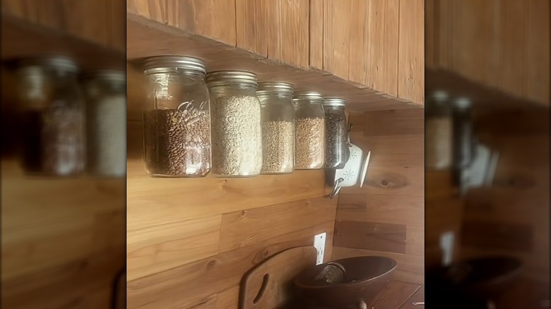 Jars suspended from the bottom of a cabinet holding dried foods