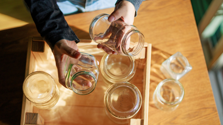 Person picking mason jars from a wooden crate of jars