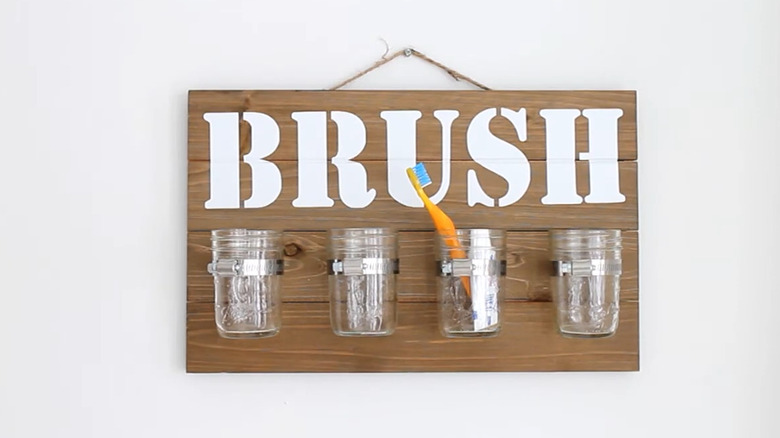 Bathroom organizer with Mason jars clamped to a wood plank background