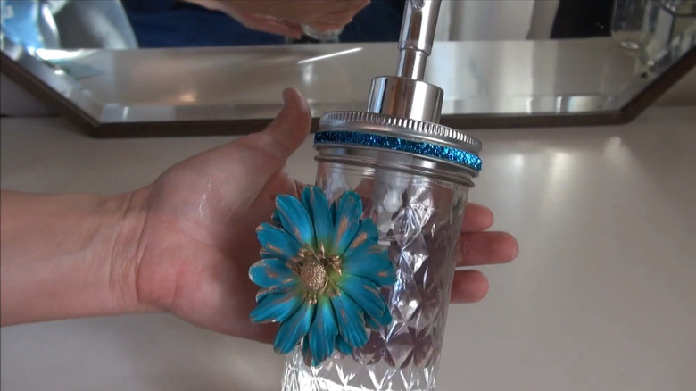 Person holding a soap dispenser made from a Mason jar