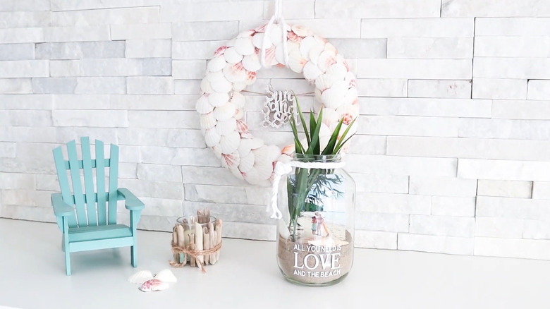 A large pickle jar turned into a photo beach keepsake display sitting on a counter with other beachy decor