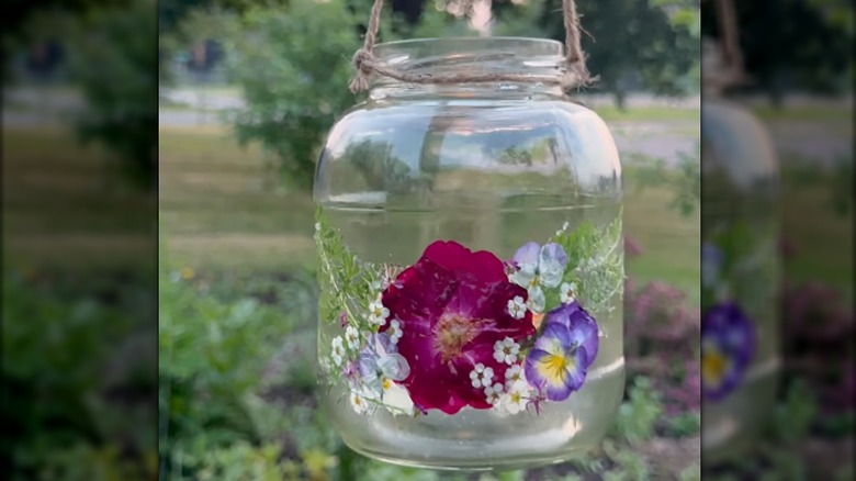 A pickle jar lantern with pressed flowers decoupaged on the outside