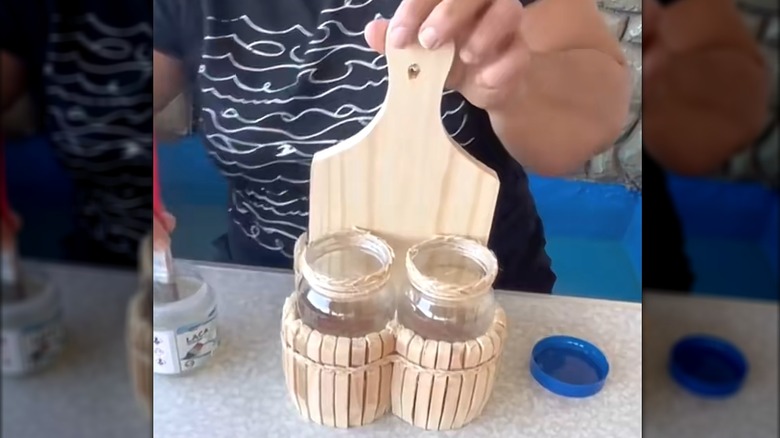Woman propping up countertop caddy made from a cutting board and pickle jars with embellishments