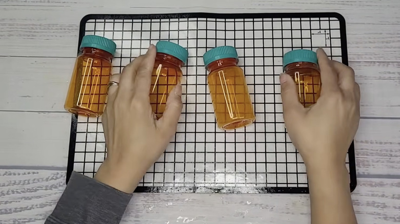 Woman's hands holding four empty pill bottles on a rustic surface