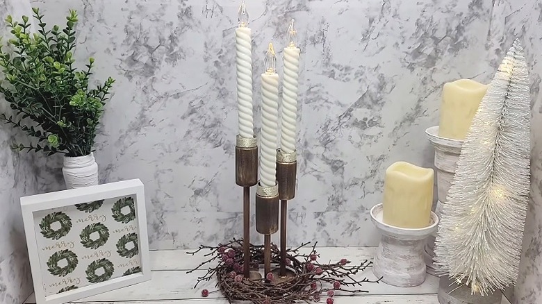 Rustic DIY candlesticks for winter on a white surface with a marble wallpaper background