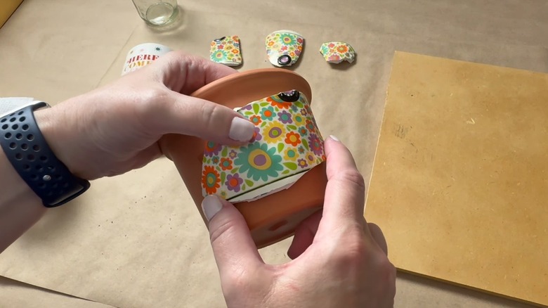 Hands building mosaic onto planter
