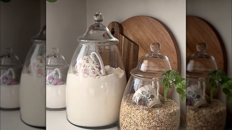 Glass jars on a countertop with dry goods and teacup scoops in them
