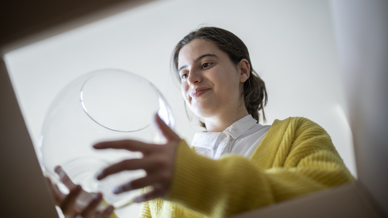 Woman lifting a glass vase out of a box