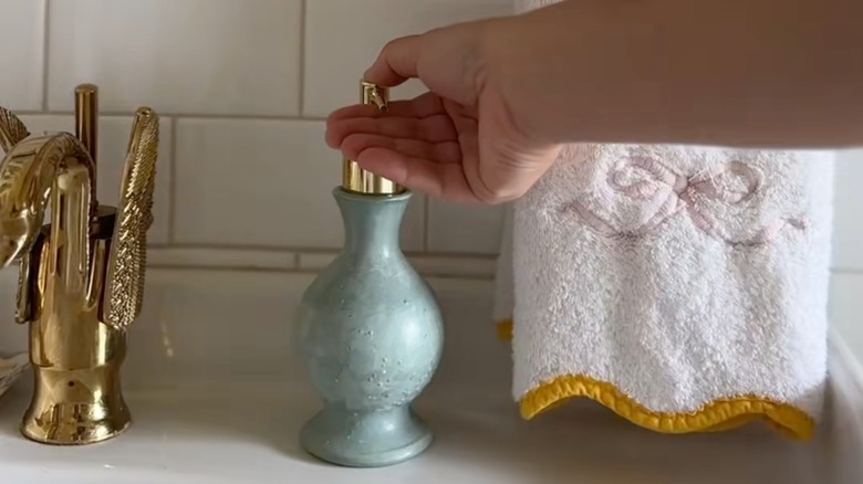 Small green vase upcycled into bathroom soap dispenser