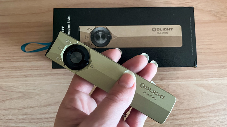 Olight ArkPro Ultra flashlight in hand with box in background