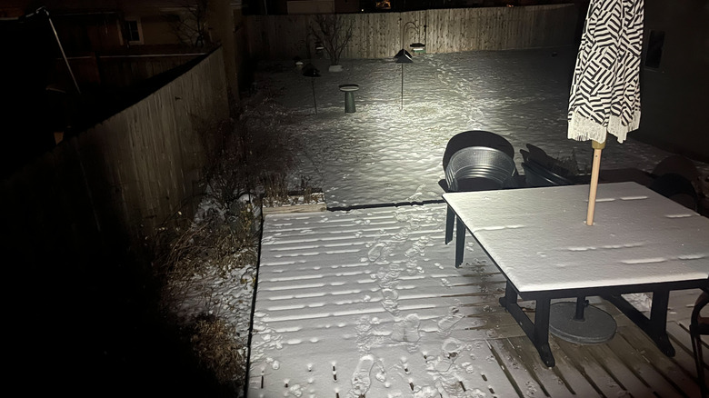 Olight ArkPro Ultra flashlight beam lighting up a backyard at night