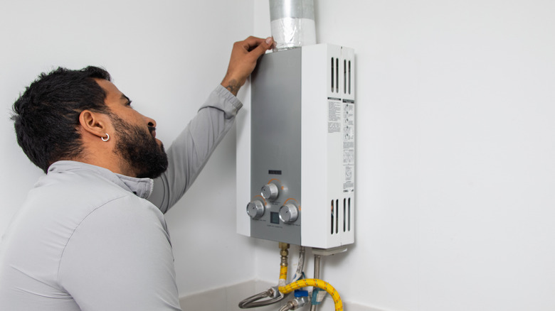 Man inspecting a tankless water heater.