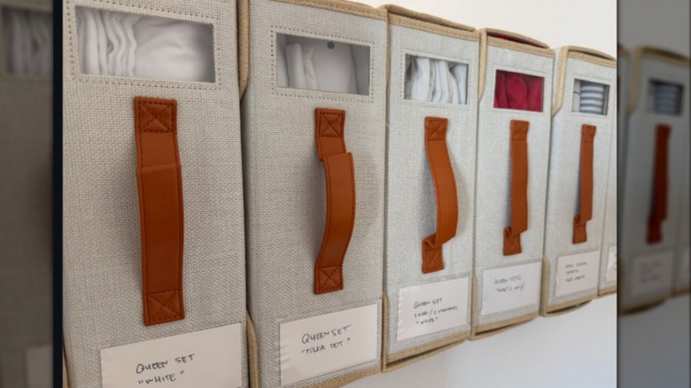 Row of labeled bed sheet organizers in closet