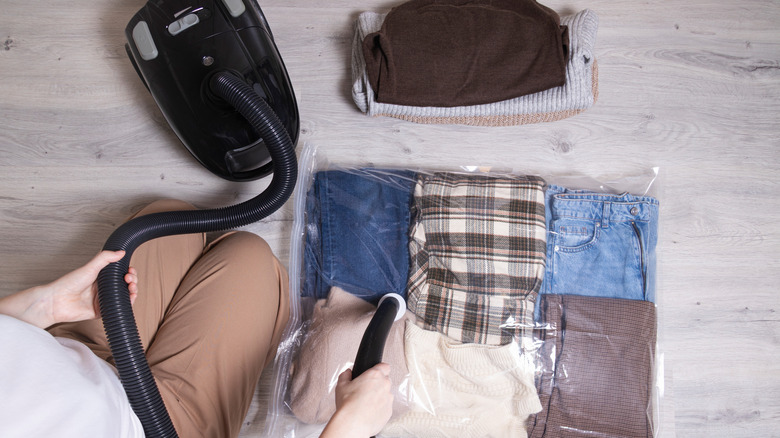 Person using vacuum to remove air from clothes storage bag