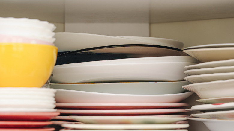cluttered stacks of dishes in a cupboard