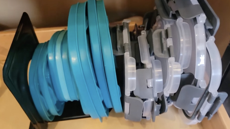 Collection of container lids behind a bookend in a drawer