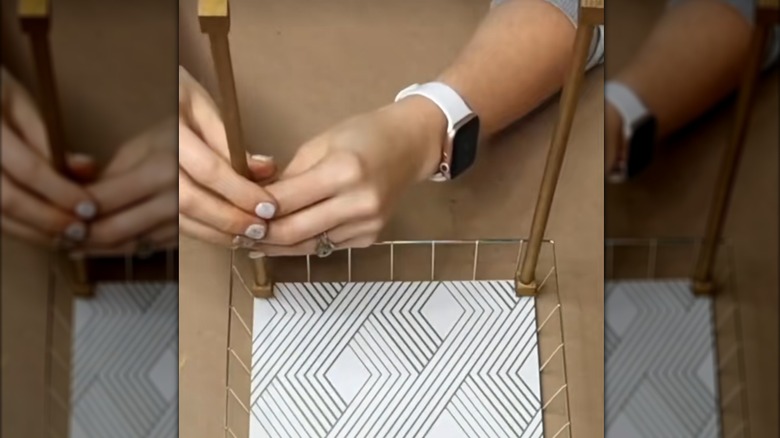 Woman assembling the supports for two-tier Dollar Tree countertop organizer with geometric pattern and gold accents