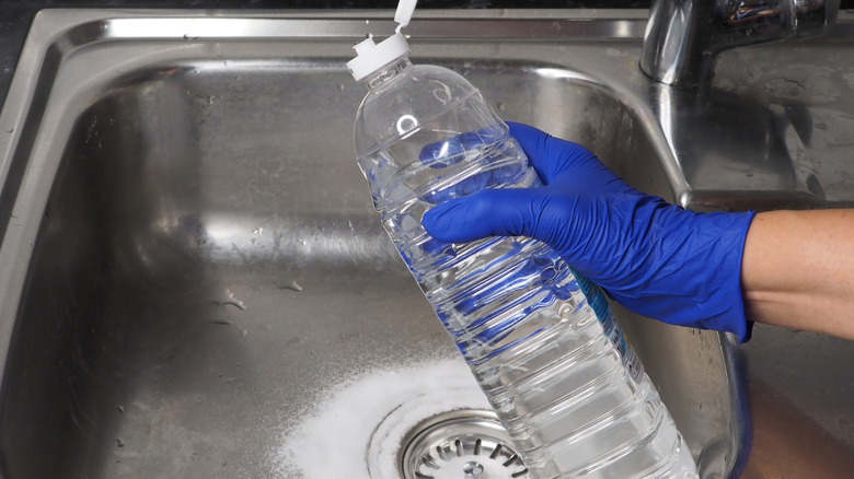 Person using baking soda and white vinegar on drain