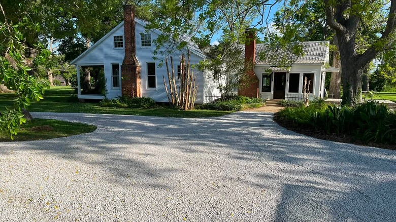 A freshly laid, crushed limestone driveway leads to a rural home