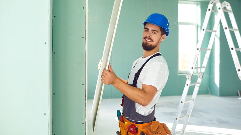 A construction worker installing a drywall panel