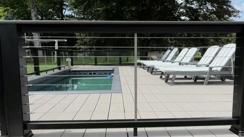 A finished pool deck using PVC boards with metal railing in the foreground.