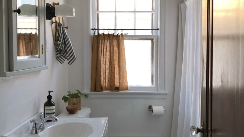 bathroom with half height cafe curtain installed in window