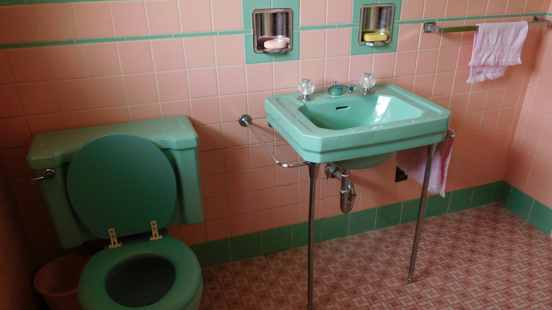 retro bathroom with green plumbing fixtures and pink tile