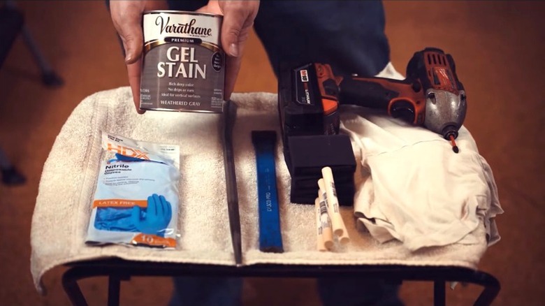 Person showing off gel stain and tools for updating wood paneled walls