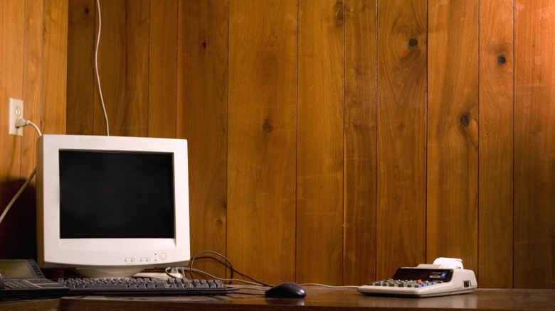 Old wood paneled walls behind dated computer setup