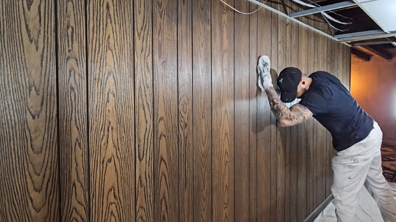 person cleaning wooden wall paneling