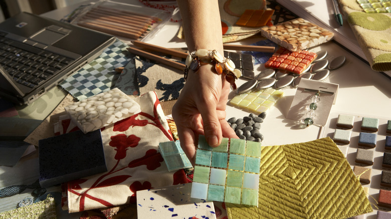 Person sorting through a table full of design finish samples like tile and fabric