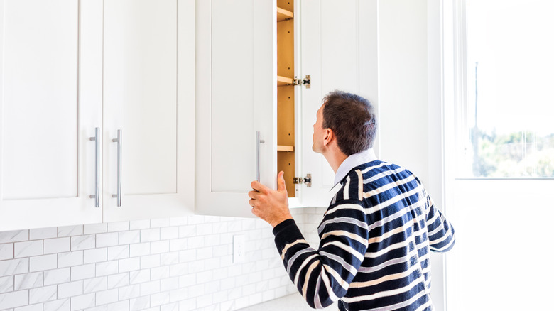 Man peering into kitchen cabinets