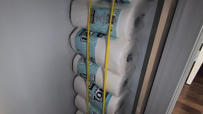 A pantry cabinet with bungees for storing paper towel rolls