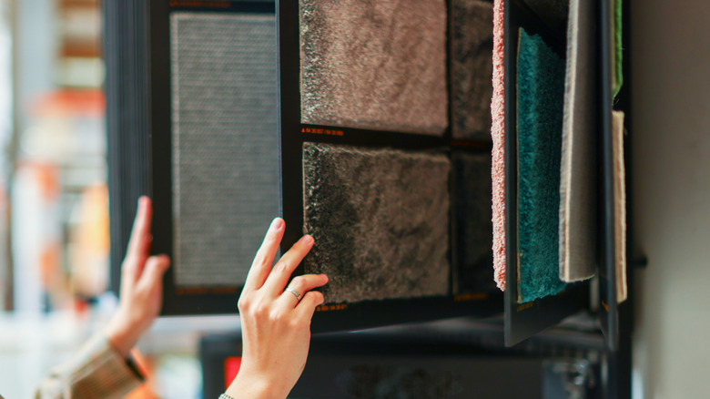 Person flipping through carpet samples at store.
