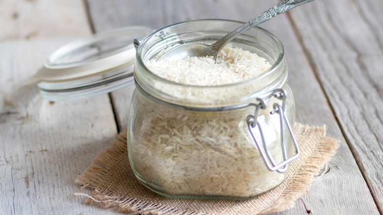 Jar full of uncooked white rice and a metal spoon