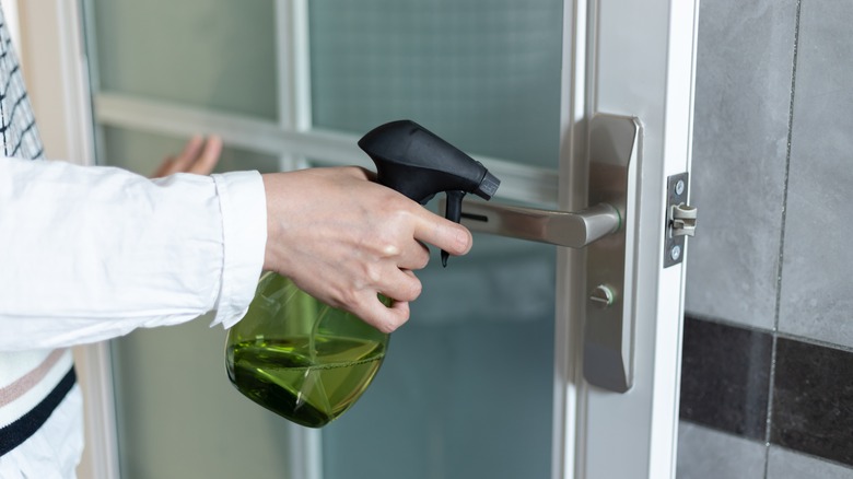 a person points a spray bottle at a door handle