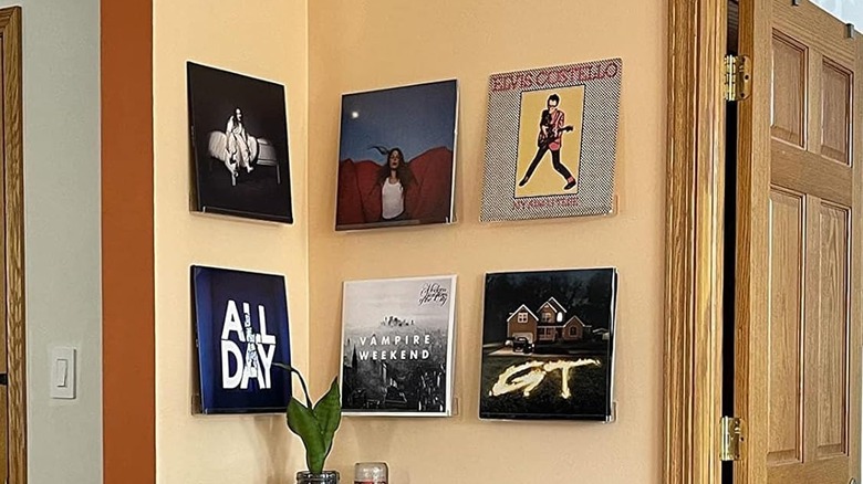 A collection of vinyl albums displayed on a wall next to a wooden door
