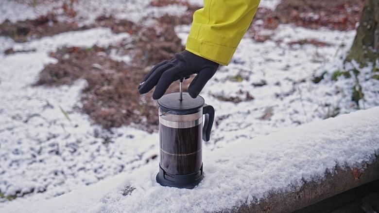 Person making french press outside in snow