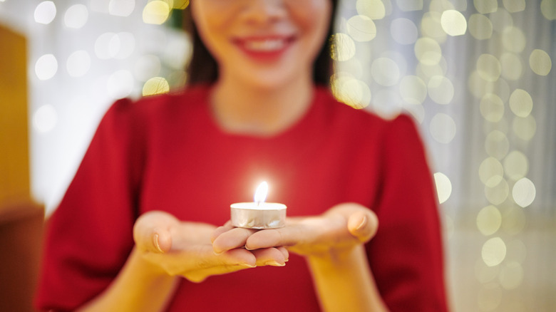 A woman smiles as she holds a tealight