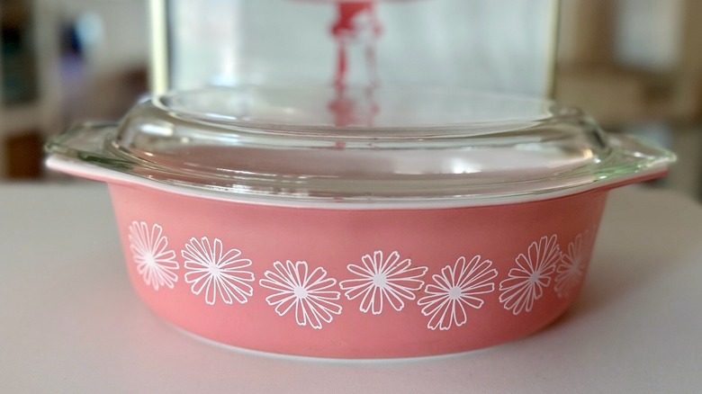 A Pyrex Pink Daisy dish with a clear lid