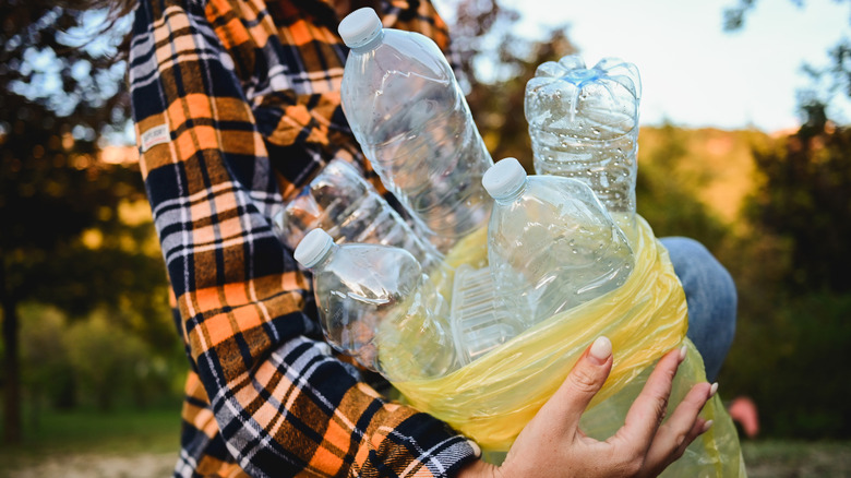 Person carrying a bag of clear plastic bottles
