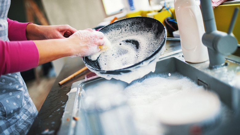 a person is scrubbing a pan in a sink full of suds